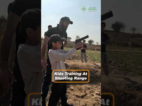 A kid aiming carefully while being guided by an expert.