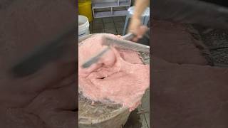 He is preparing handmade beef balls and pounding the pork filling